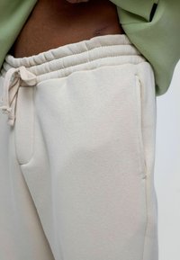 Lichtbeige joggingsbroek met een elastische tailleband en een trekkoord, uitgerust met zijzakken en een zachte, gestructureerde stof.