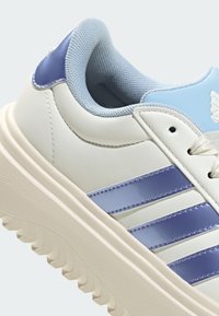 Bijele tenisice s laganim plavim naglascima, teksturiranog gumenog đona, gornjište od glatke kože i tri sjajne plave pruge.