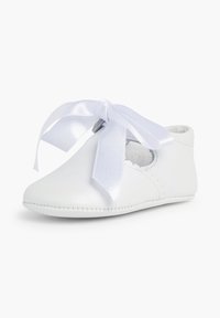 Zapato de cuero blanco con puntera redonda, corte lateral y detalle de lazo. Presenta bordes cosidos y una textura suave.