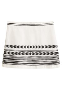 Falda blanca hasta la rodilla con bordado de patrón geométrico y de hojas en negro horizontal cerca del dobladillo y la cinturilla.