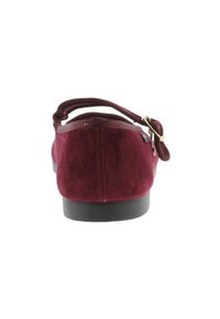 Zapato de ante burdeos con tacón bajo, tira elástica y puntera redondeada. Tiene una textura suave y una suela de goma negra.