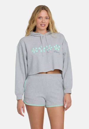 Grijze cropped hoodie van zachte stof met bloemrijke borduursels in muntgroen, gecombineerd met bijpassende grijze shorts met muntkleurige accenten.