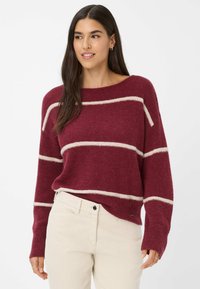 Bordeaux gebreid sweater met crèmekleurige strepen, brede ronde halslijn en geribbelde boorden. Combinatie met lichtgekleurde broeken, met een subtiele logodetail.