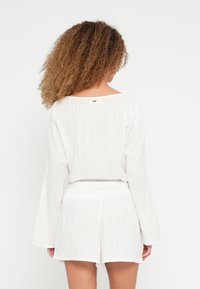 Σετ λευκής υφής για χαλάρωση που περιλαμβάνει κοντομάνικη μπλούζα με φαρδιά λαιμόκοψη και σορτς με ελαστική μέση, με κάθετες ρίγες.