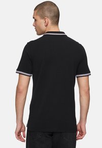 Zwarte poloshirt met een klassieke kraag, voorzien van gestreepte accenten op de kraag en mouwen. Gemaakt van katoen met een soepele textuur.