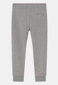 Pantalones de chándal de algodón gris con un corte ajustado, cinturilla elástica y puños de canalé. Cuenta con un bolsillo trasero. Textura lisa en toda la prenda.