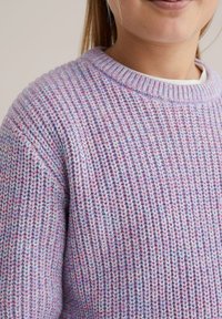 Mujer con un suéter de punto en tonos pastel morado y azul, mostrando la textura de punto y el cuello acanalado, con parte de su rostro y cabello visibles.