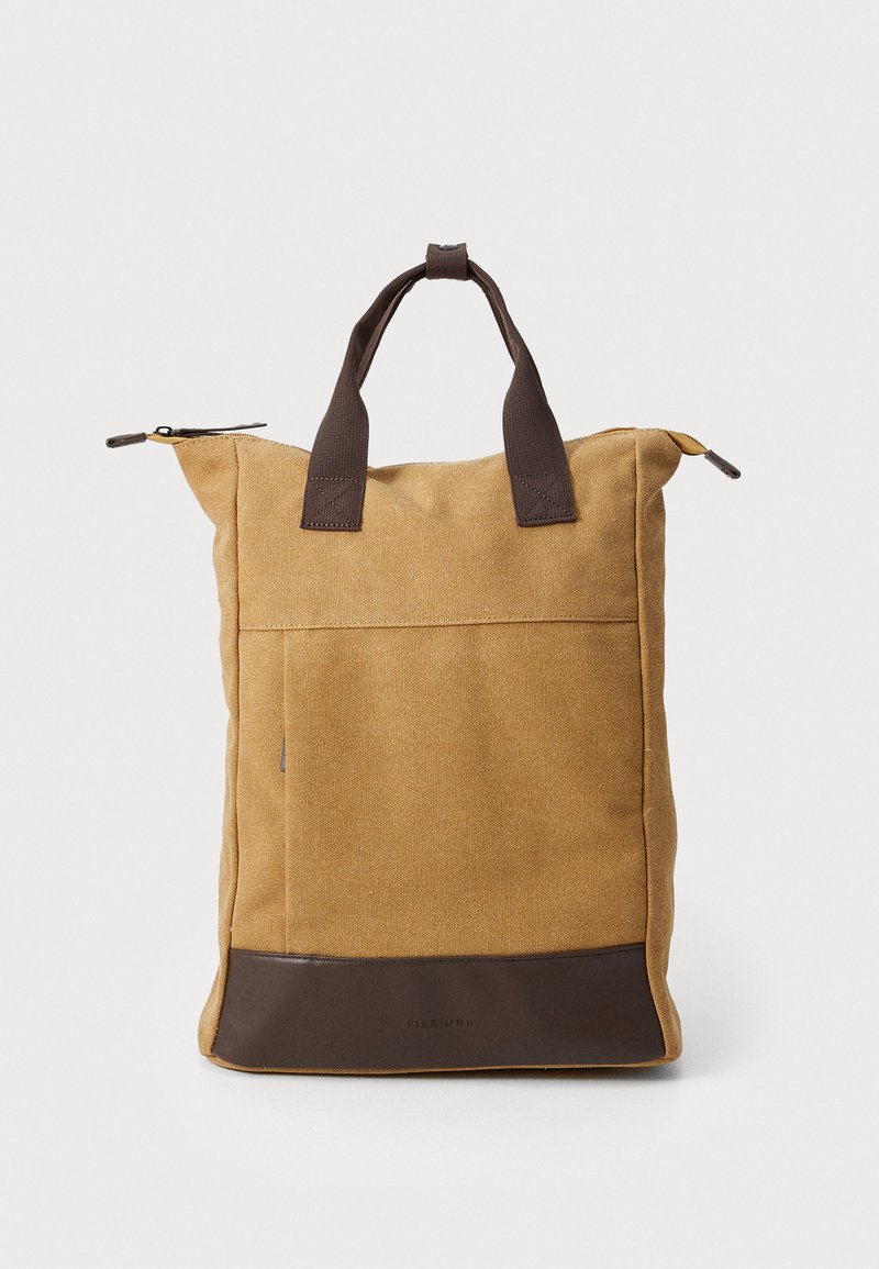 Brown canvas tote bag with dark brown accents, a zippered top, sturdy short handles, and a front pocket. Textured finish throughout.