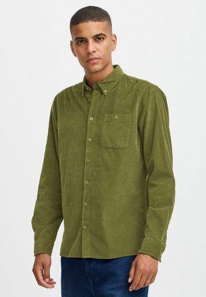 Green corduroy shirt with a button-down collar, front pocket, and button closure, featuring a textured surface and slim fit.