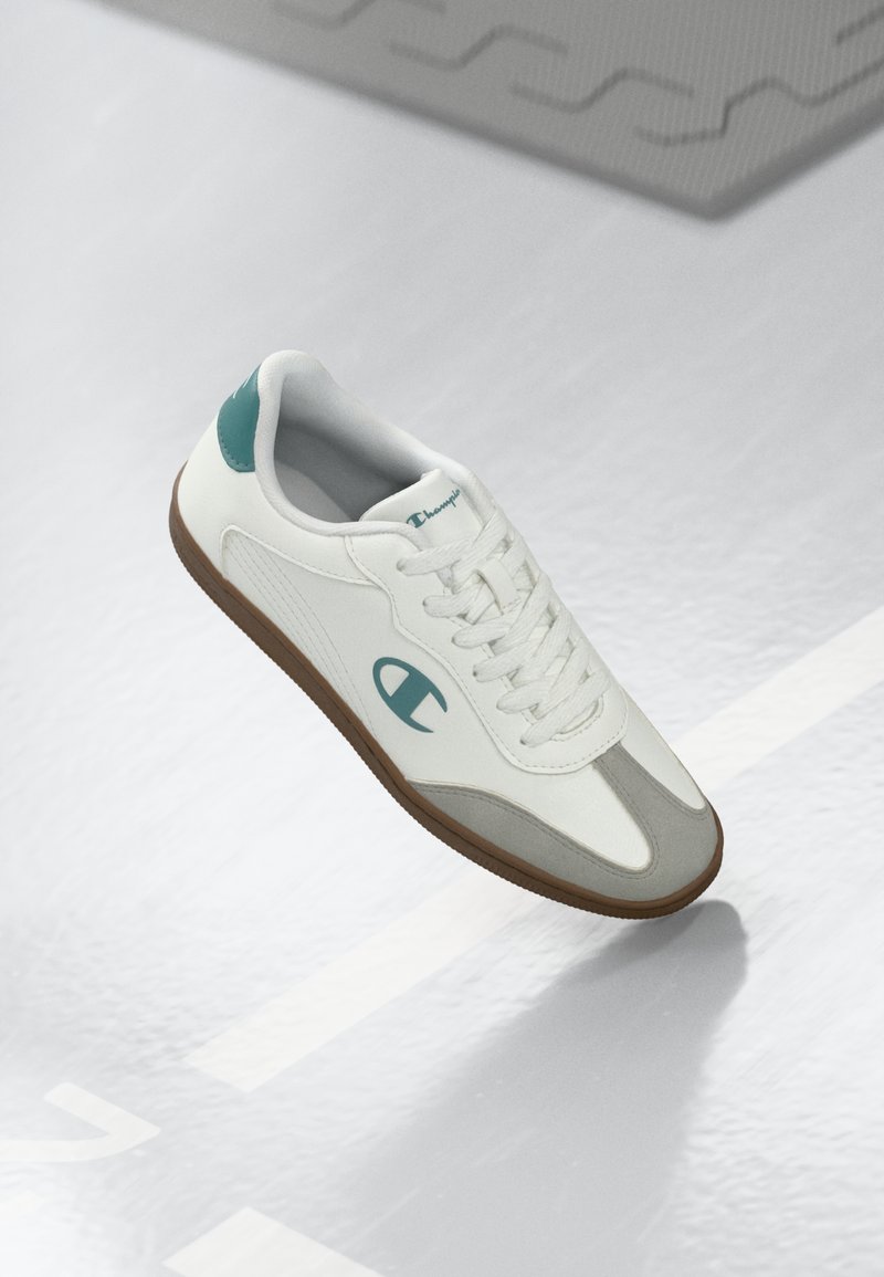 Hvit sneaker med lysegrå detaljer, med en teksturert lærøvre, rund tå, teal-bekledning på hælen og gummisåle.