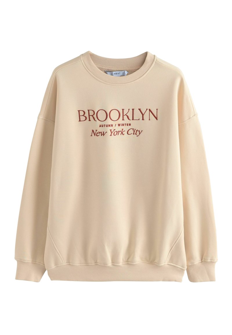 Beige sweatshirt met ronde hals, drop shoulder ontwerp en ribgebreide manchetten. Bevat roodbruin tekst: "BROOKLYN HERFST/WINTER New York City."