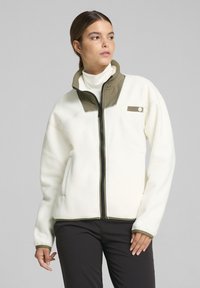 Kurtka polarowa w kolorze off-white, z wysokim kołnierzem oraz oliwkowymi akcentami na ramionach i kieszeni, zapinana z przodu na zamek błyskawiczny, z ściągaczami na mankietach.