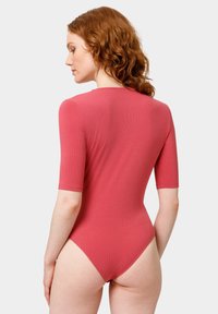 Prążkowany bodysuit z krótkim rękawem w koralowym kolorze, z wysokim tyłem oraz dopasowanym krojem z wycięciem na pośladkach. Gładka tekstura.