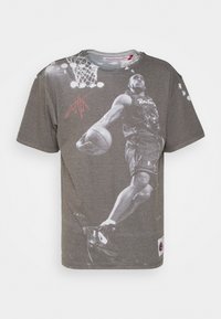 Grå bomulds t-shirt med et stort grafisk tryk af en basketballspiller i bevægelse, med fremhævede detaljer og signatur. Korte ærmer.