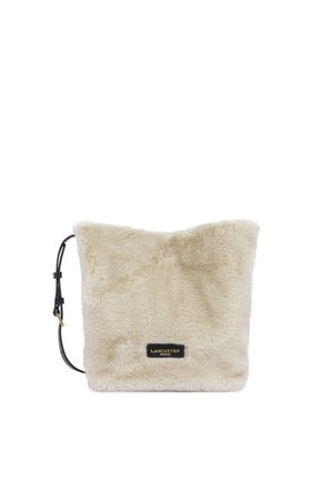 Sac bandoulière carré beige en fausse fourrure avec bandoulière noire réglable et petite étiquette noire indiquant Lancaster Paris à l’avant.
