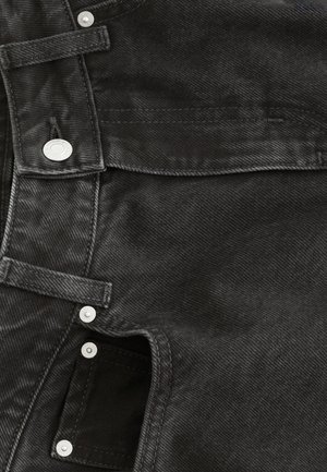 Black denim fabric features a textured surface, with silver snap buttons and a zipper at the side, showcasing a structured design.