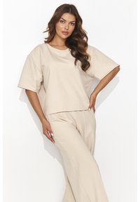 Beżowa bluzka z krótkim rękawem i szerokim dekoltem, zestawiona z luźnymi, dopasowanymi spodniami. Miękki materiał o gładkiej fakturze i minimalistycznym wzornictwie.
