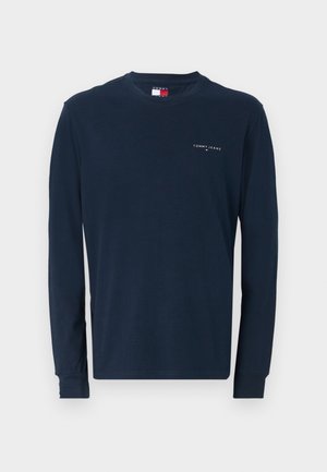 Mørkeblå langærmet T-shirt i bomuld. Har en rund halsudskæring og et lille hvidt "TOMMY JEANS" logo på venstre bryst. Blød tekstur.