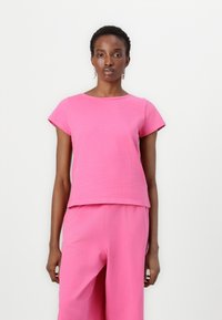 Kortermet, crew-neck rosa topp laget av et mykt stoff, med en avslappet passform og rett kant, sammen med matchende løse bukser.