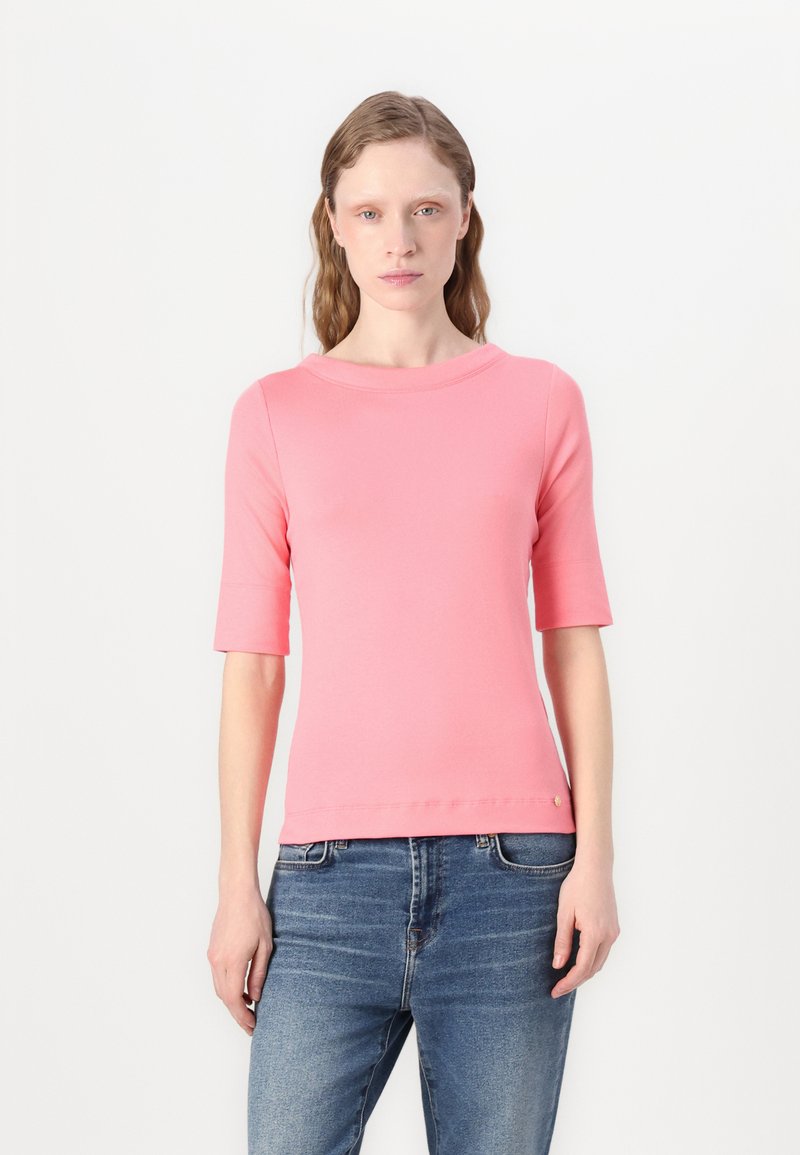 Roze T-shirt met korte mouwen in een gladde katoenmix, met een ronde halslijn en een klein logoaccent aan de zoom, gecombineerd met blauwe jeans.