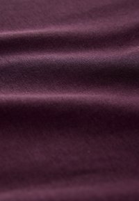 Tissu texturé de couleur prune profonde, présentant des plis doux et une surface lisse avec un léger éclat et un motif de tissage serré.