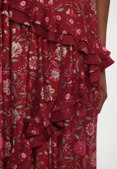 Tejido floral rojo con bordes ondulados; presenta flores rosas y grises con hojas verdes. Textura suave, el diseño en capas realza el interés visual.