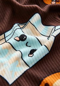 Patterned fabric featuring a brown ribbed background with cartoonish faces in soft blue, beige, and black accents.