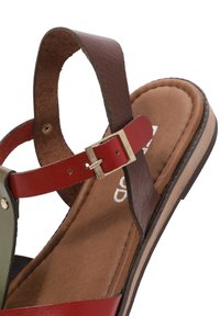 Leather sandal with red, brown, and green straps. Features metallic buckle, cushioned tan footbed, and a flat brown sole.
