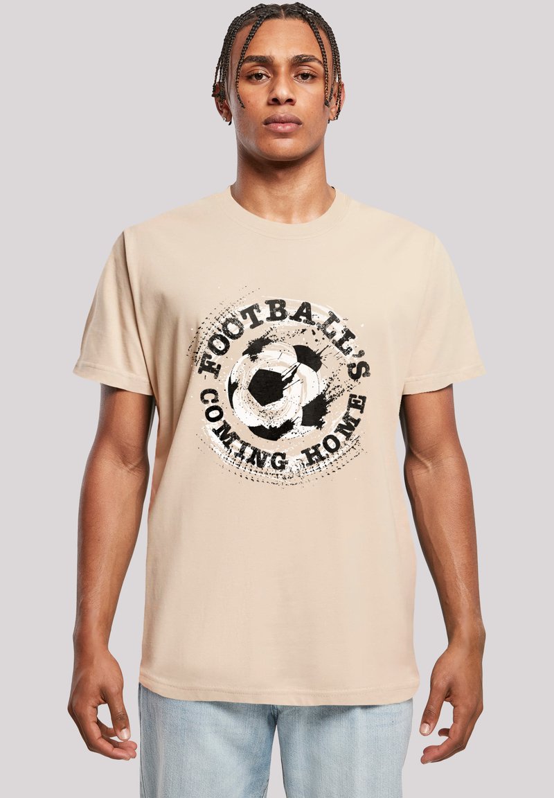 Beige cotton t-shirt featuring a circular graphic with a soccer ball and text "FOOTBALL'S COMING HOME" in black, with distressed accents.