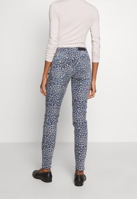 Úzké džíny s modrým leopardím potiskem, se středně vysokým pasem, bezešvým designem a černou známkou na zadní straně.