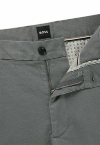 Gray patterned trousers featuring a button closure, zipper fly, and branded logo on the waistband. Lined interior with logo print.