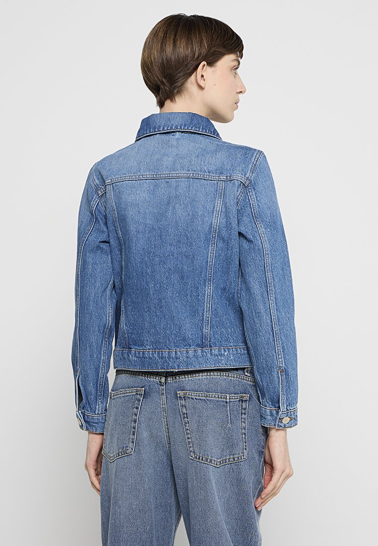 Jeansjacke in Hellblau mit klassischem Kragen, langen Ärmeln und Rückenpasse mit Nahtdetails. Hat einen cropped Schnitt und zwei seitliche Taschen.