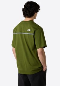 Olivengrünes Baumwoll-T-Shirt mit Rundhalsausschnitt, kurzen Ärmeln und einem weißen horizontalen Logo-Band über dem oberen Rücken.
