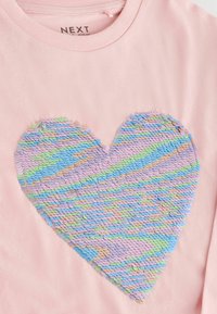 Roze katoenen t-shirt met een groot hartontwerp van meerkleurige pailletten in pastelkleuren blauw, paars en groen.