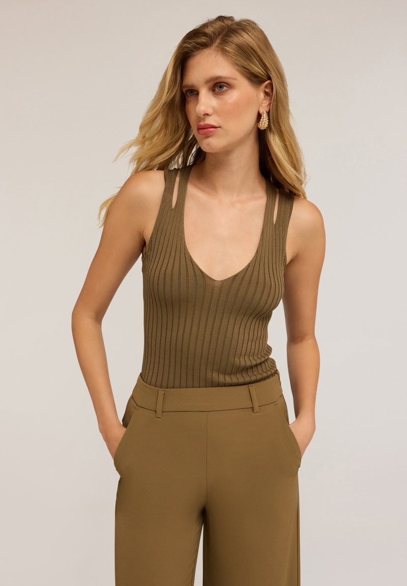 Bruine geribbelde mouwloze body met een diepe V-halslijn en uitsnijdingen op de schouders, gecombineerd met bijpassende high-waisted broek.