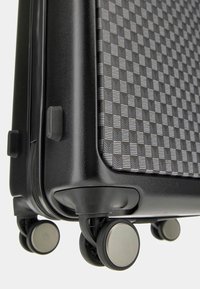 Black wheeled suitcase with a textured checkered pattern, featuring a glossy finish and smooth edges. Includes four spinner wheels for mobility.