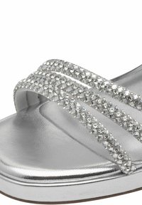 Infradito silver con tre cinturini decorati da cristalli. La tomaia ha una superficie metallica liscia. Suola imbottita per il comfort.
