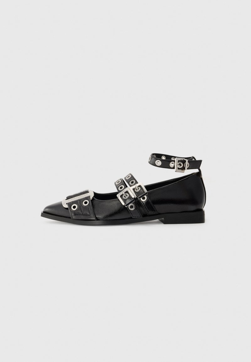 Black pointed flat shoe with three silver buckled straps, ankle strap with eyelets, and metallic detail on toe area.