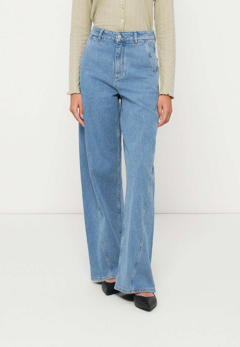 Visoke, široke kavbojke iz svetlo modrega denima, s klasičnim petkotnim dizajnom in diskretnimi podrobnostmi sprednjega šiva.