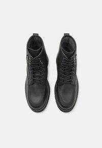 Schwarze Leder-Stiefeletten mit runder Zehenpartie, kontrastierenden Nähten und Schnürung an der Vorderseite. Verfügt über eine Zuglasche und ein weiches Innenfutter.