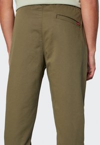 Pantalones verde oliva con una textura suave, que cuentan con un bolsillo trasero con una pequeña etiqueta roja, y una cinturilla elástica para mayor comodidad.