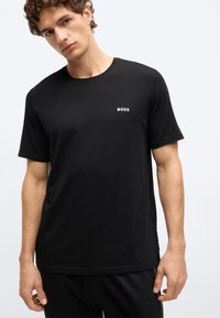 Μαύρο T-shirt με στρογγυλή λαιμόκοψη από μαλακό ύφασμα και κοντά μανίκια. Διαθέτει μικρό λευκό λογότυπο "BOSS" στο στήθος. Απλός, λιτός σχεδιασμός.