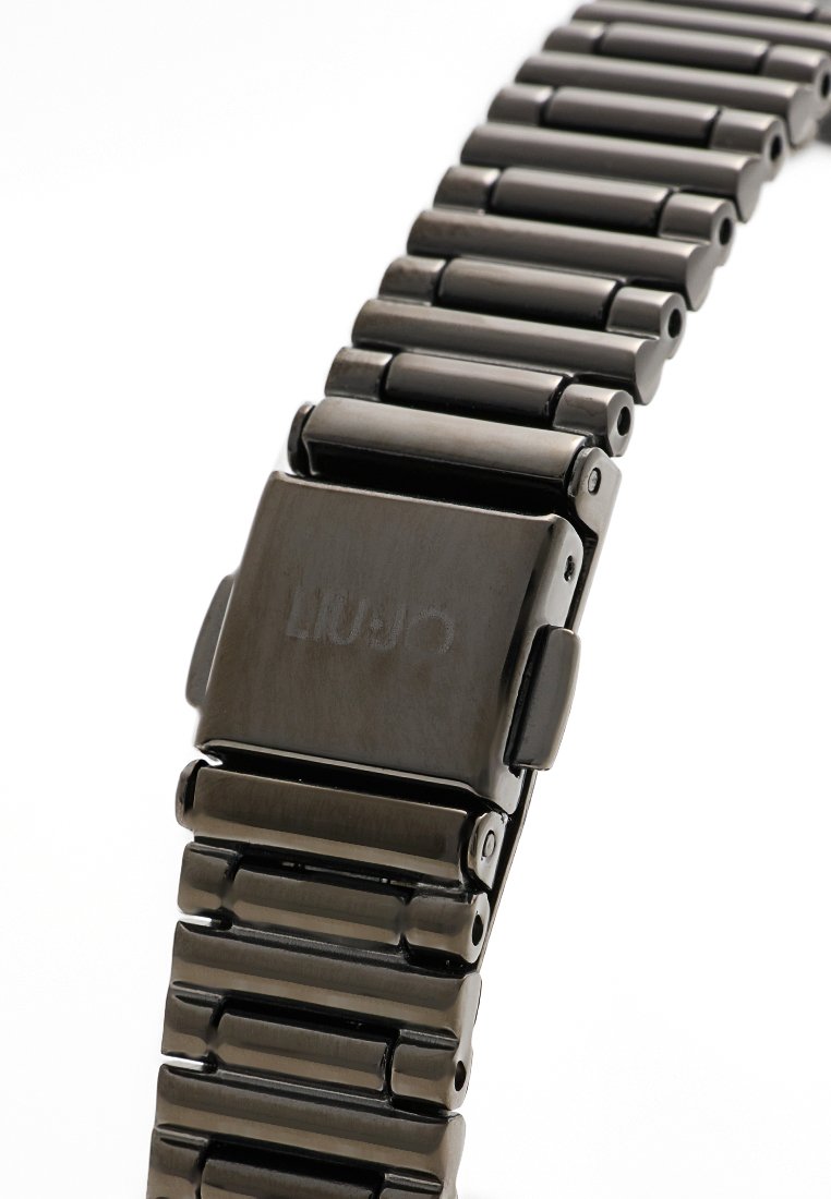 Metallischer schwarzer Uhrenarmband mit einem rechteckigen Verschluss, der einen eingeprägten Markennamen zeigt, segmentierten Gliedern und seitlichen Freigabetasten.