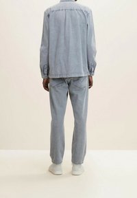 Giacca di jeans azzurro chiaro e jeans a taglio largo abbinati. La giacca ha una chiusura con bottoni e maniche lunghe. Tessuto testurizzato, design casual.