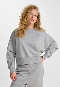 Felpa grigia corta con vestibilità rilassata, polsini e orlo a costine, texture morbida, caratterizzata da un piccolo logo sulla parte anteriore.