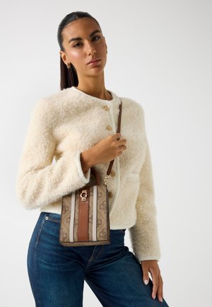 Chaqueta de piel sintética beige con cuello redondo y botones, combinada con un bolso marrón a rayas que cuenta con un logo y un asa corta.