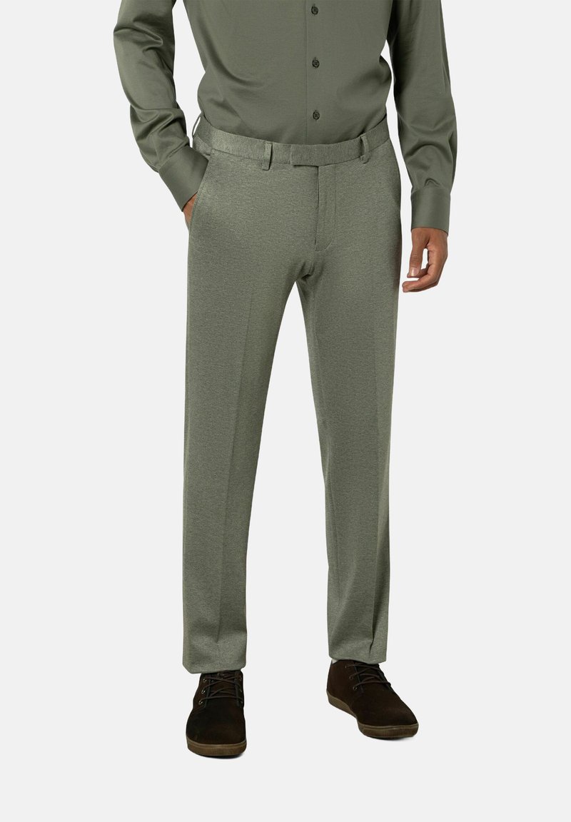 Olijfgroene, op maat gemaakte dresspants met een gladde textuur, rechte pijpen en riemlussen, gecombineerd met een bijpassend overhemd met knopen en donkere schoenen.