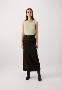 Λαχανί ριπ κορμάκι συνδυασμένο με μια μακριά, σκούρα καφέ τζιν φούστα. Μαύρες μπότες με τακούνι ολοκληρώνουν την εμφάνιση. Απλός, μίνιμαλ σχεδιασμός.