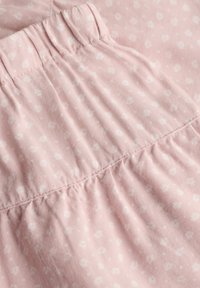 Tissu rose doux avec petit motif floral blanc et détail de ceinture élastique froncée.