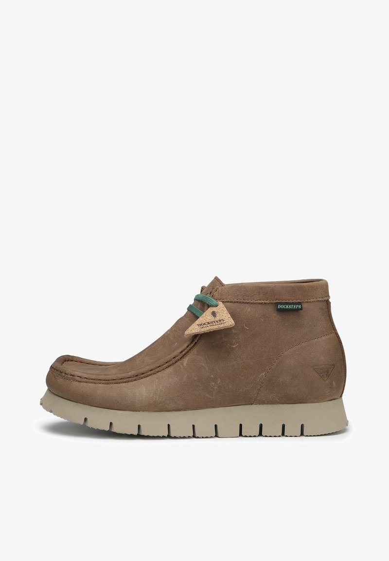 Stivale alla caviglia in pelle marrone con punta arrotondata, dettagli in pizzo verde e etichetta con logo. Presenta una suola in gomma testurizzata con scanalature profonde.